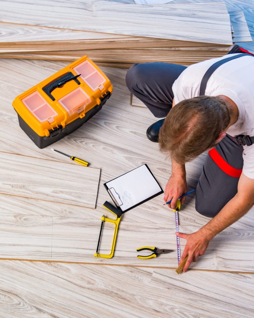 Man laying laminate flooring in construction concept