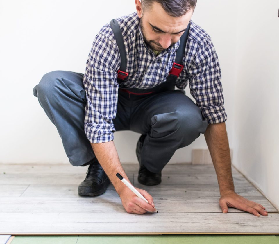 Young worker laying a floor with bright laminated flooring boards